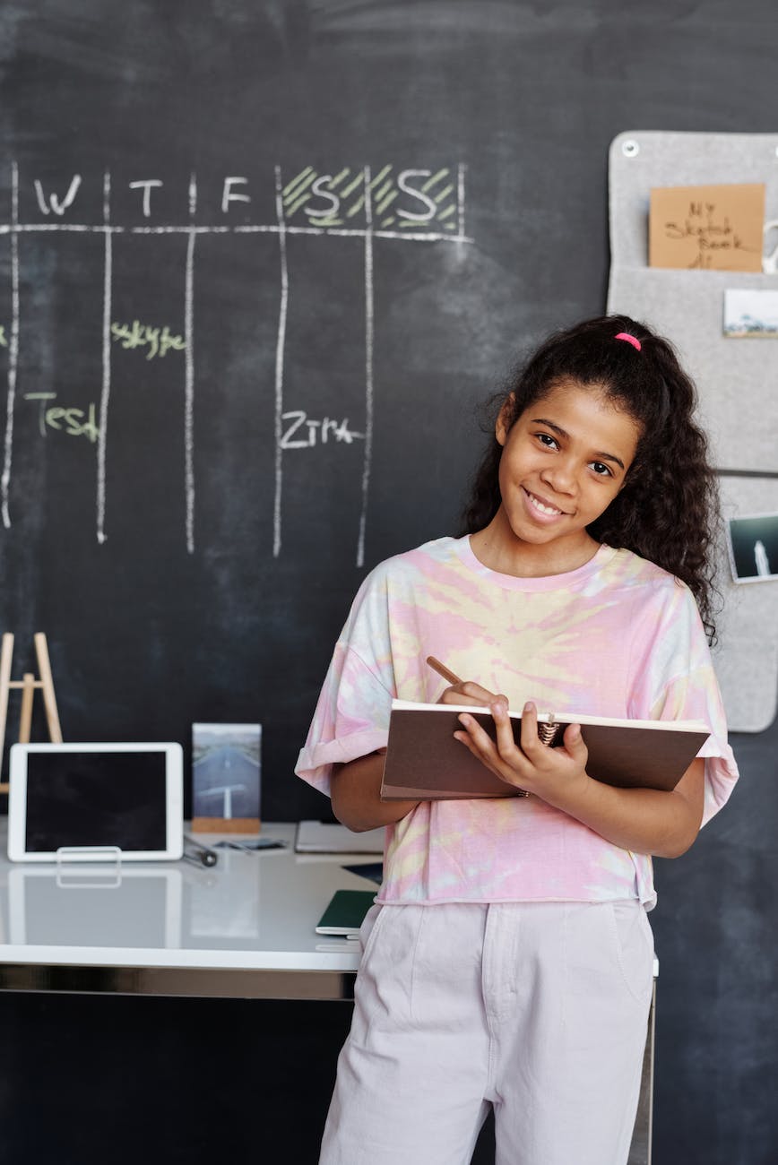 girl in pink and white crew neck t shirt holding brown notebook