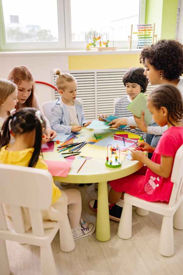 children sitting on chairs in front of table with art materials